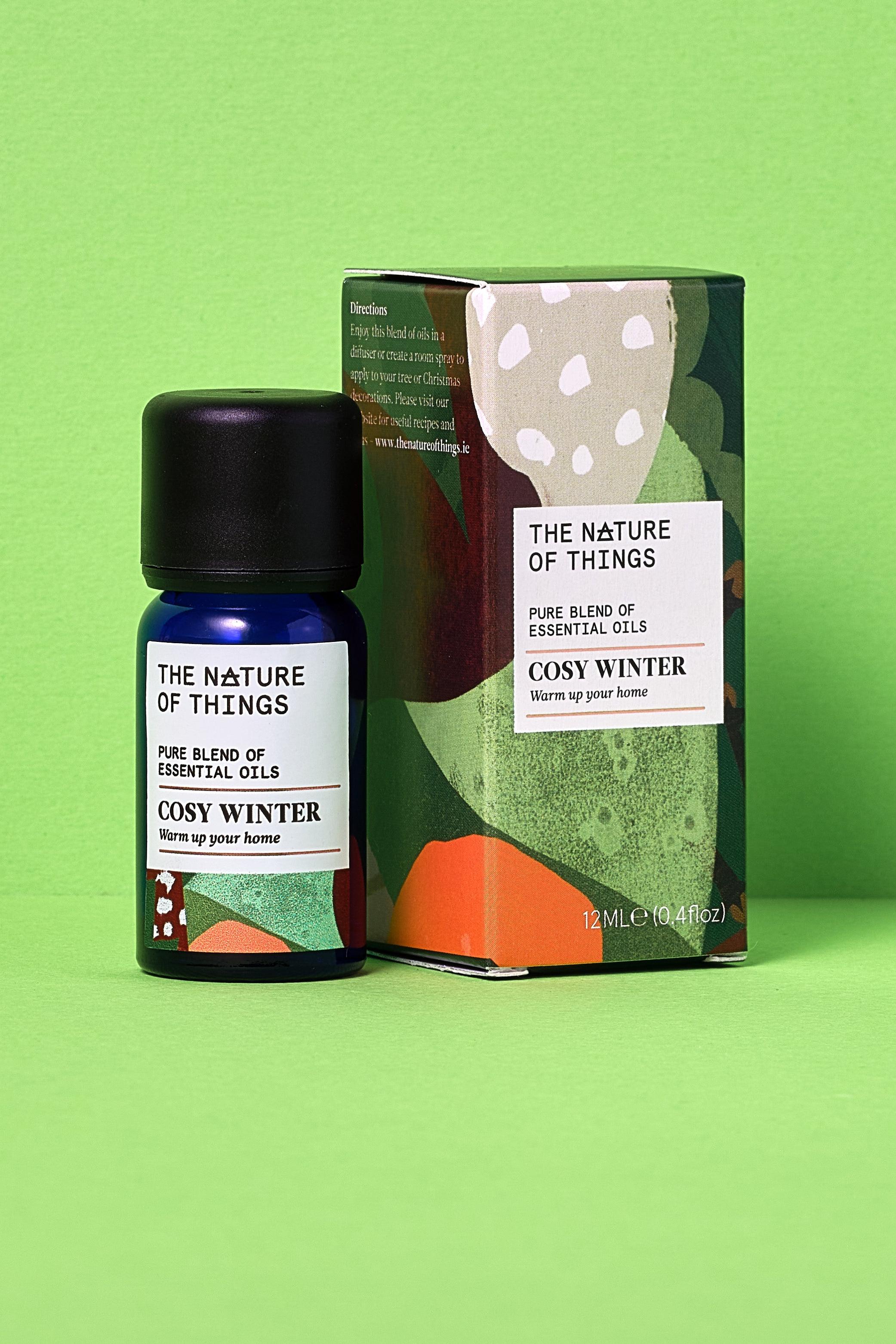 Cosy winter essential oil bottle and packaging on a green background
