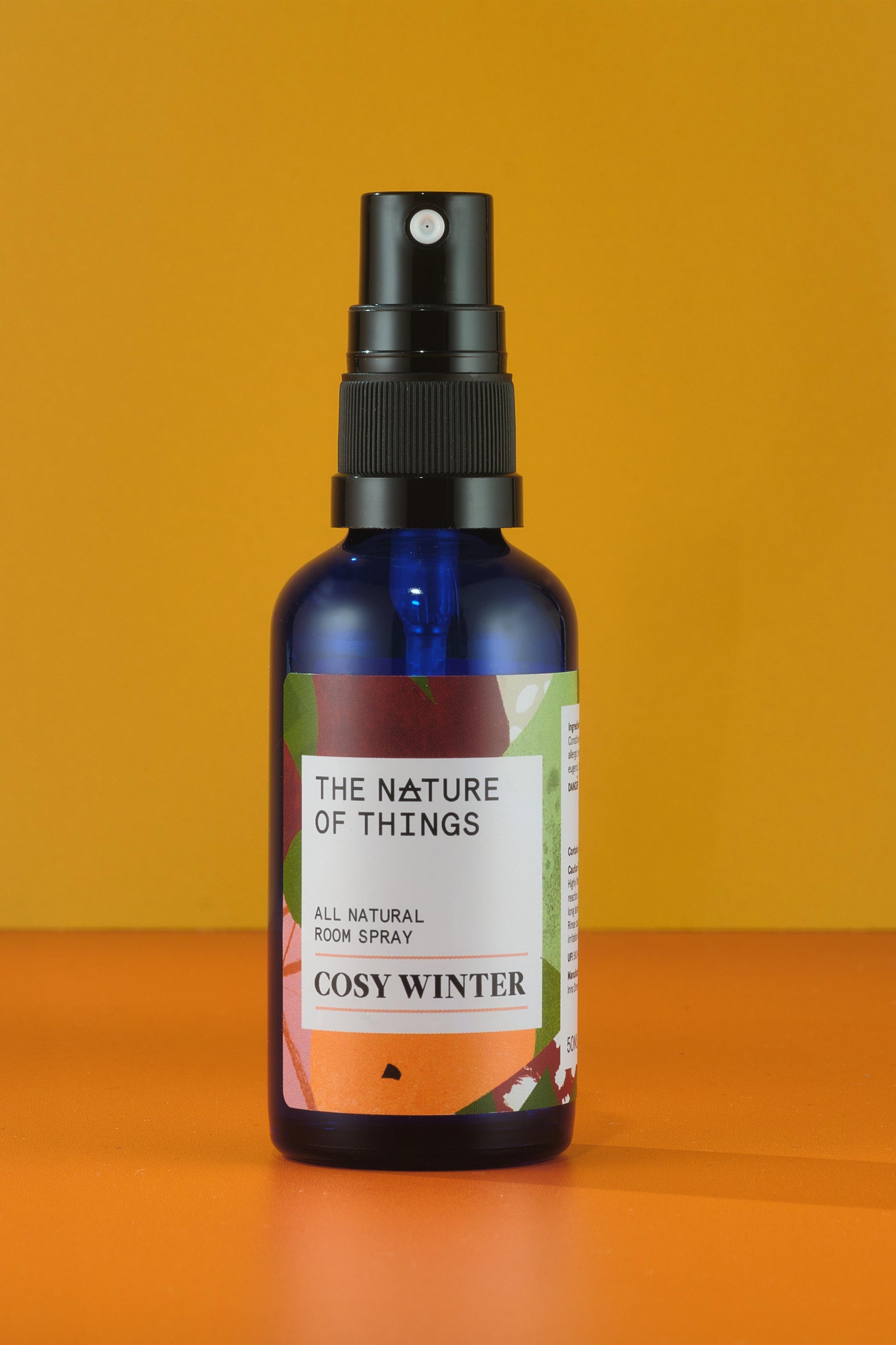 Bottle of 'Cosy Winter' room spray by 'The Nature of Things' on an orange background