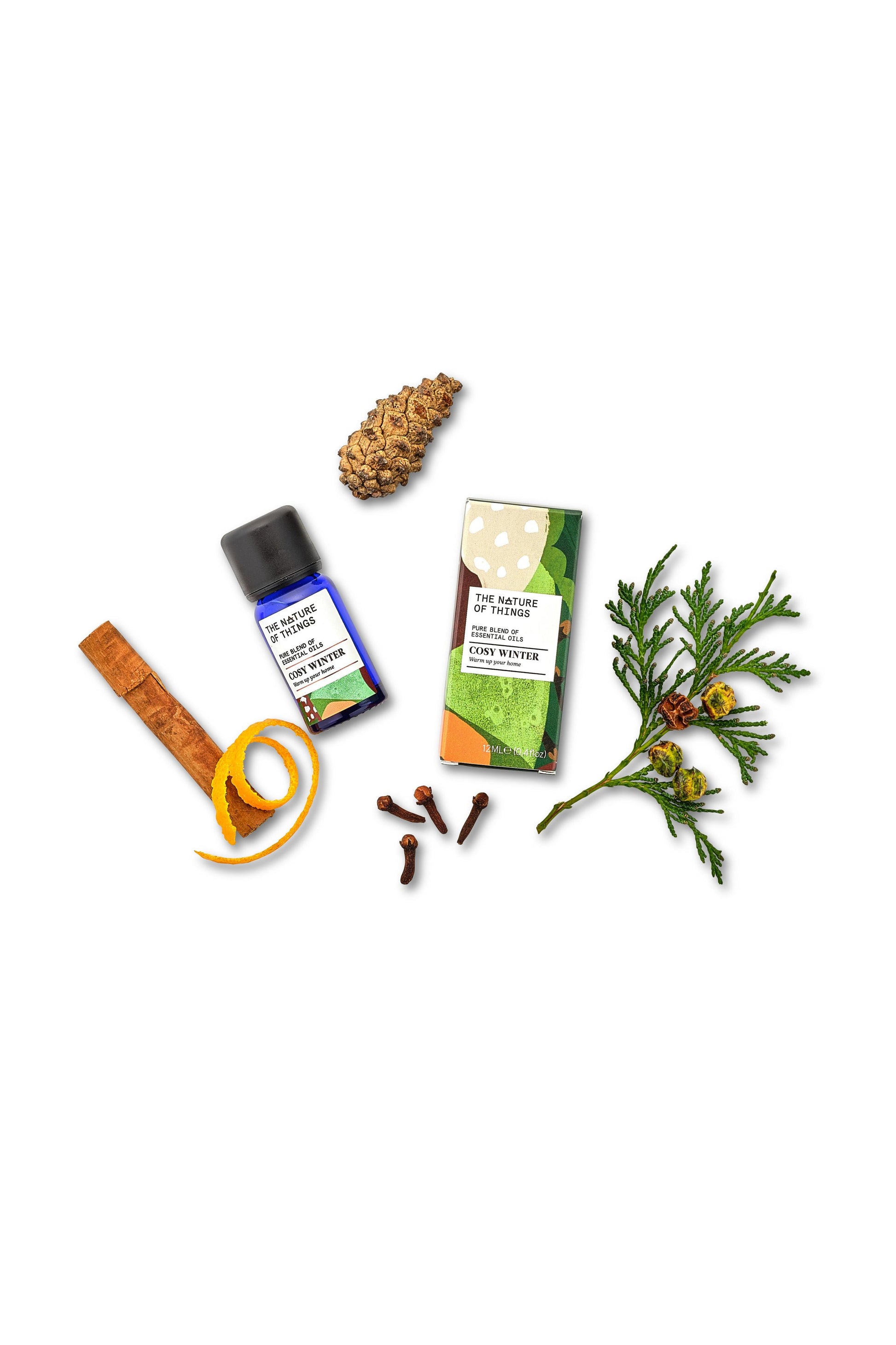 Essential oil packaging with cinnamon, cloves, and a pine cone on a white background