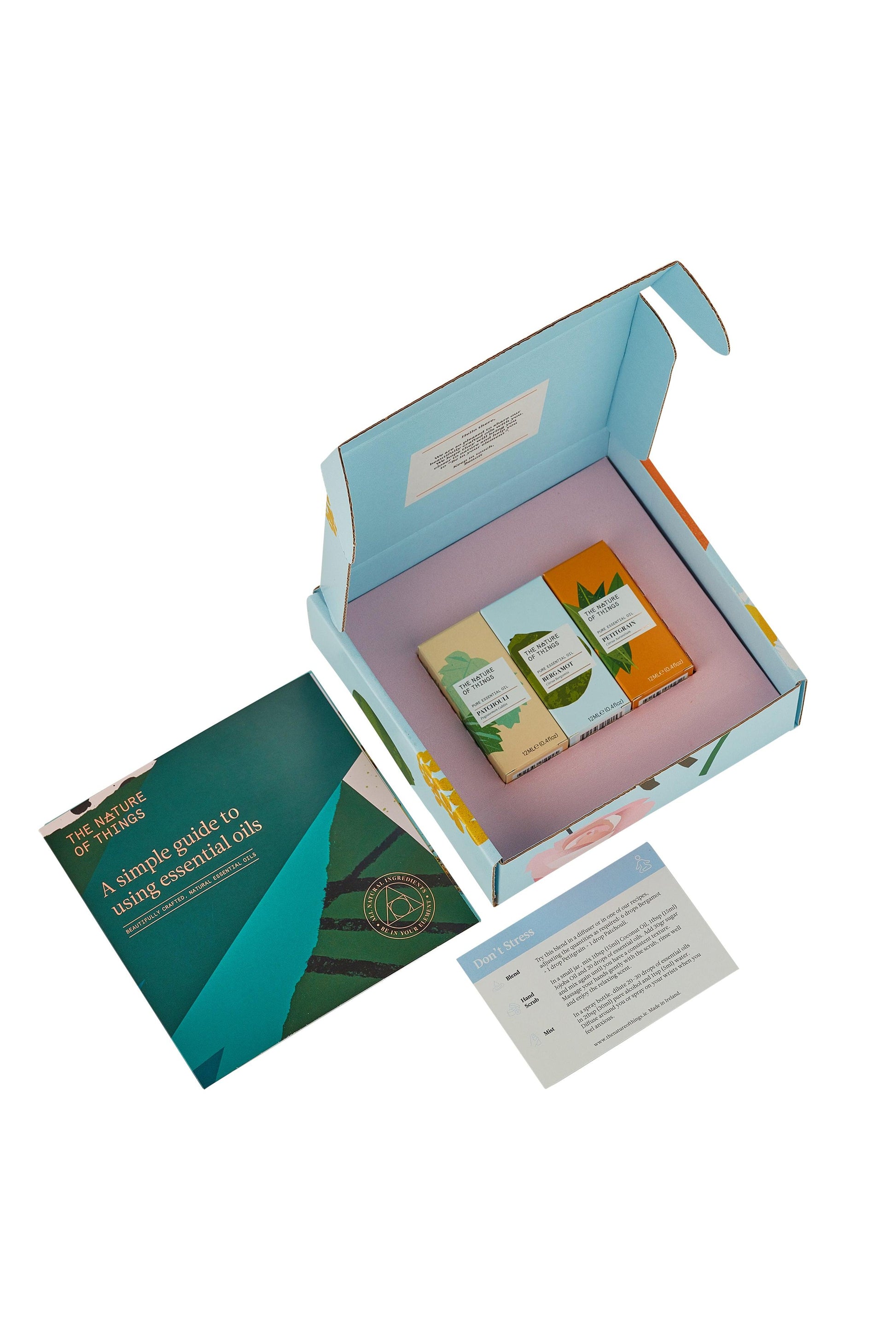 Open box containing essential oils and a guide on a white background