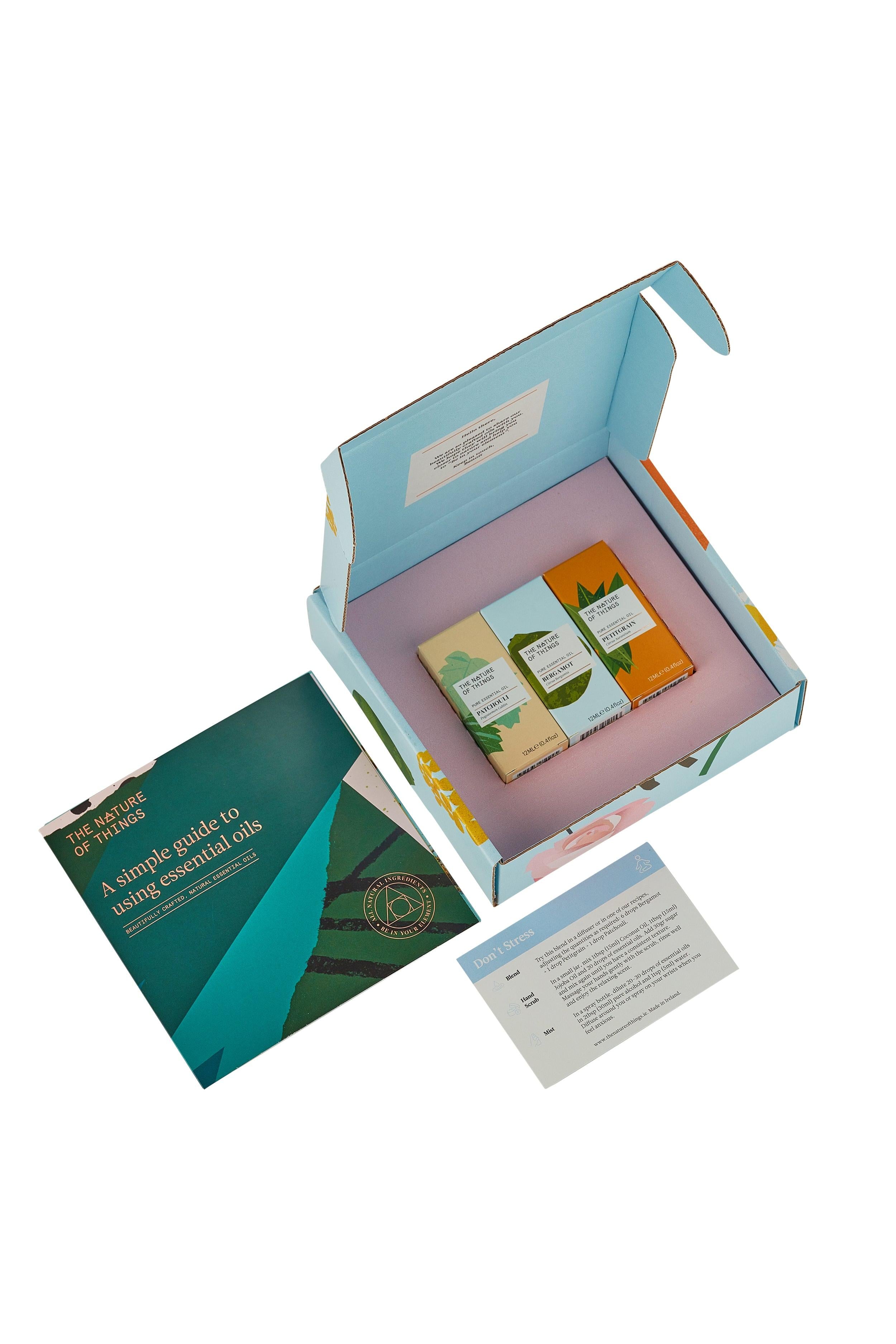 Open box containing essential oils and a guide on a white background