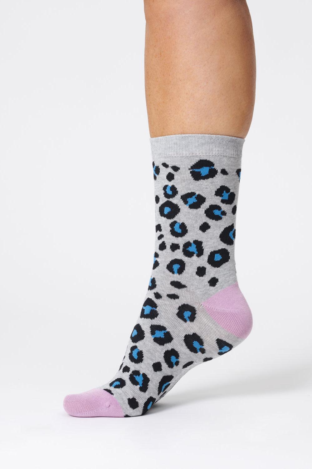 One foot wearing grey bamboo sock with blue animal print spots and lilac heel and toes.