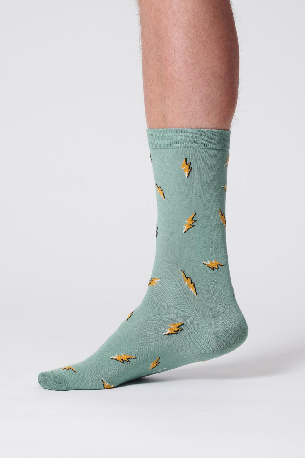 Close-up of a foot wearing a lagoon green sock with lightning bolt patterns.