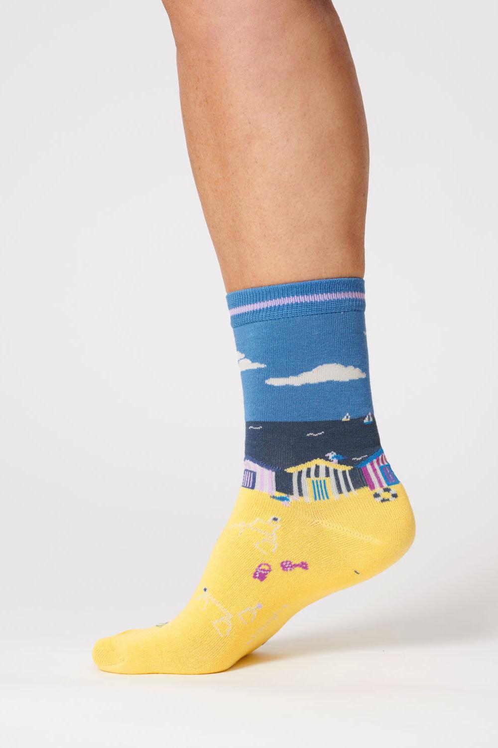 Close-up of a foot wearing a sea blue sock with a beach hut design.