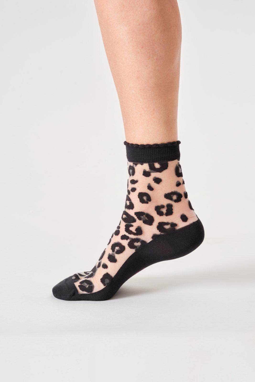 Sheer bamboo sock with leopard print and black trim worn by a person on a light gray background