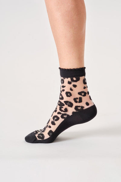 Sheer bamboo sock with leopard print and black trim worn by a person on a light gray background