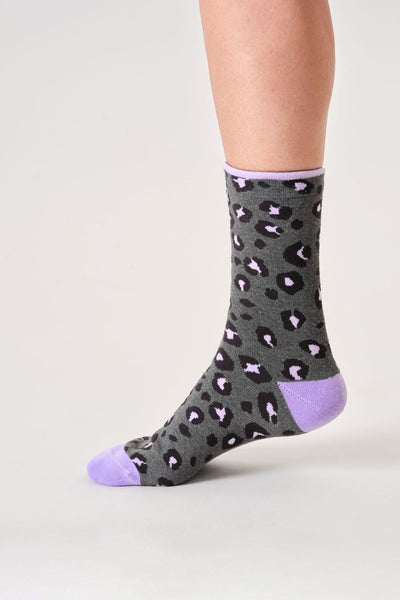 Gray organic cotton socks with purple accents worn by a person on a light gray background