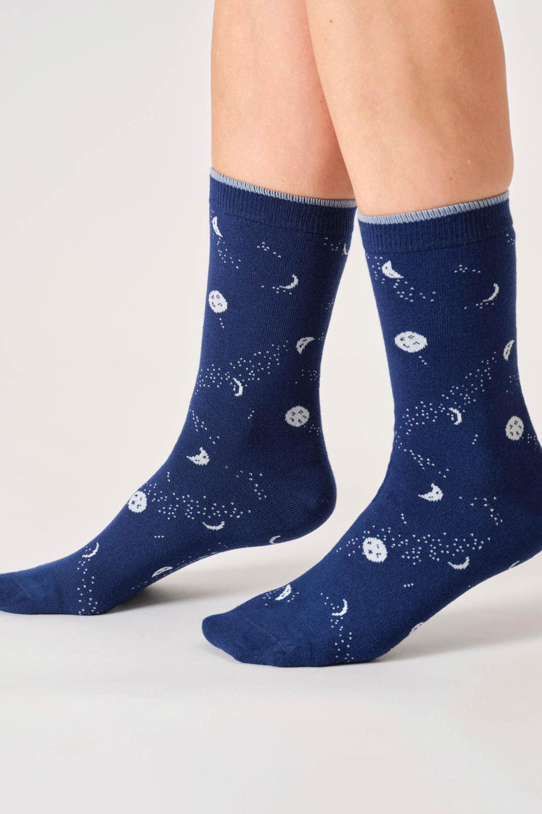 Navy blue socks with celestial pattern worn by a person on a light gray background