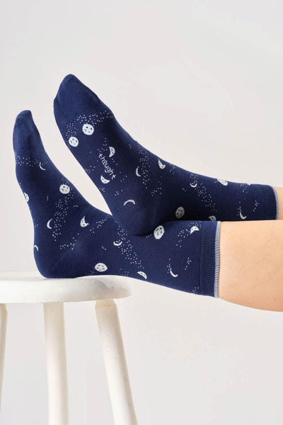 Navy blue socks with moon and star pattern worn by a person on a white background
