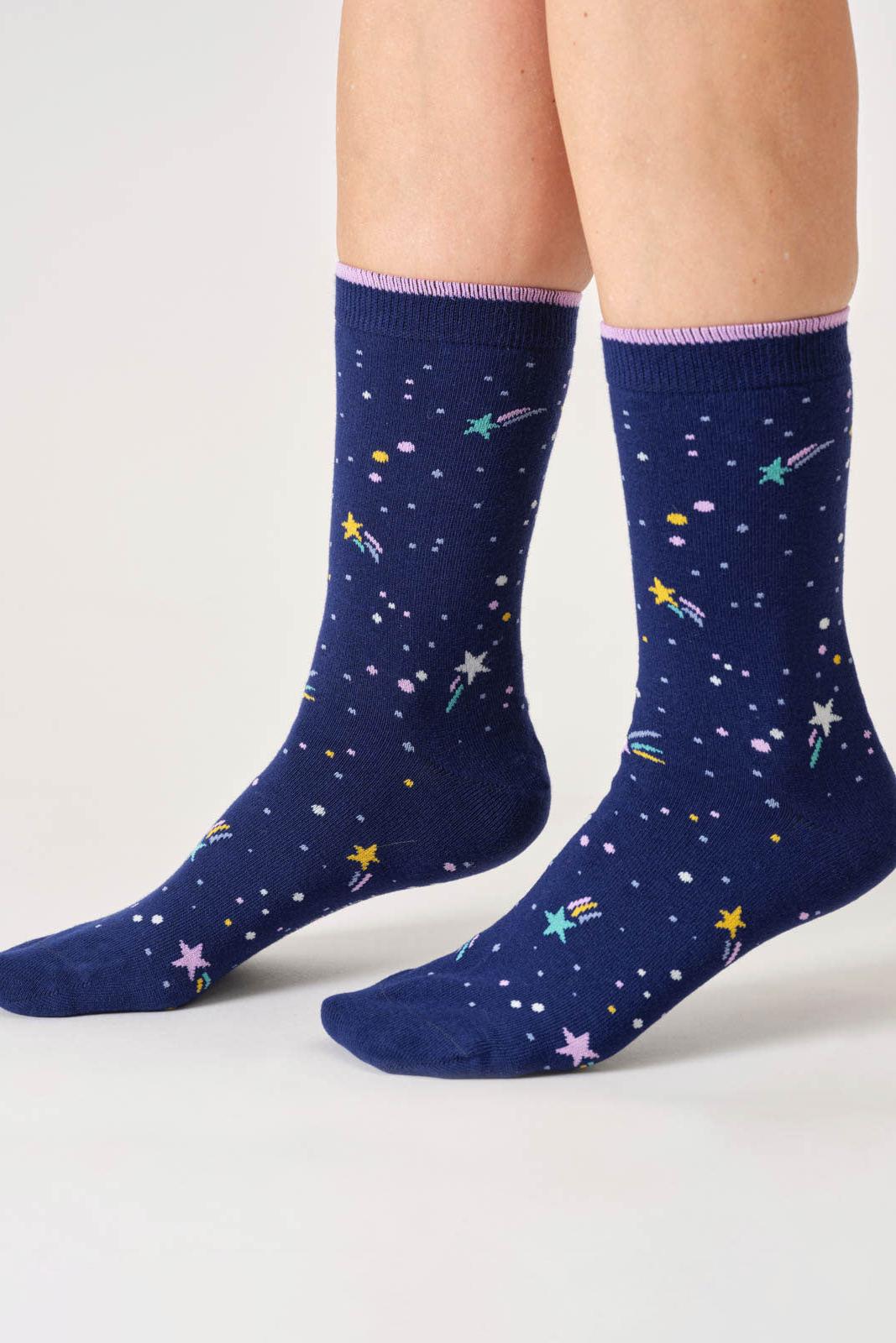 Navy blue socks with star and planet pattern worn by a person on a light gray background