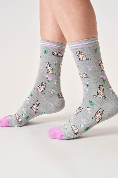 Gray socks with cat patterns worn by a person on a light background