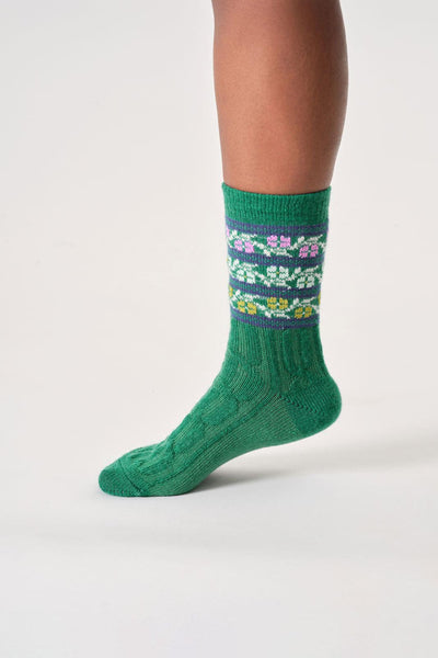 Green wool sock with floral pattern worn by a person on a white background