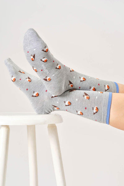 Gray socks with robin pattern worn by a person on a white stool against a light gray background