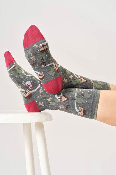 Bamboo patterned socks with red christmas theme worn by a person on a white chair.