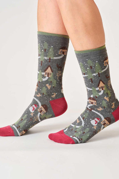 Person wearing festive socks with winter village design on a light gray background