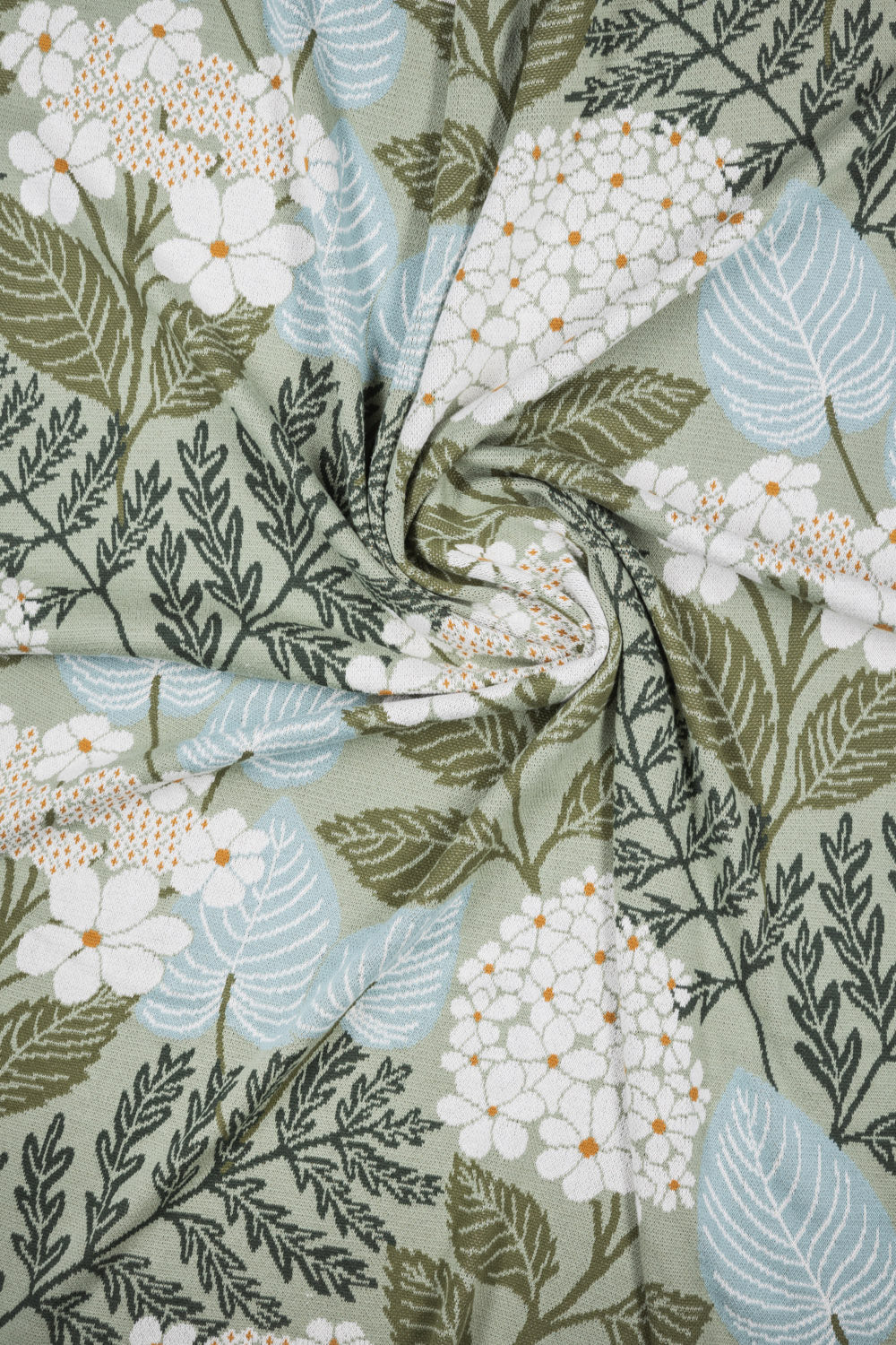 Organic cotton fabric with a floral and leaf pattern on a green background