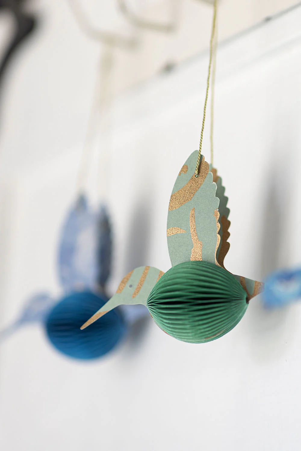 Decorative paper bird ornament with gold accents on a white background