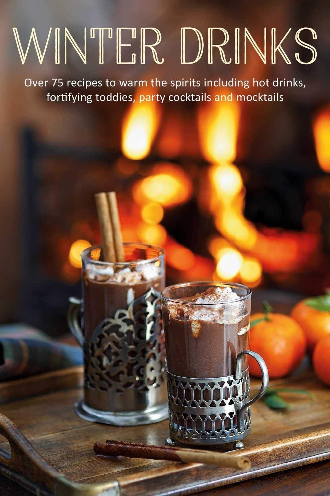 Book cover of 'Winter Drinks' with hot chocolate and oranges on a wooden tray in front of a fireplace.