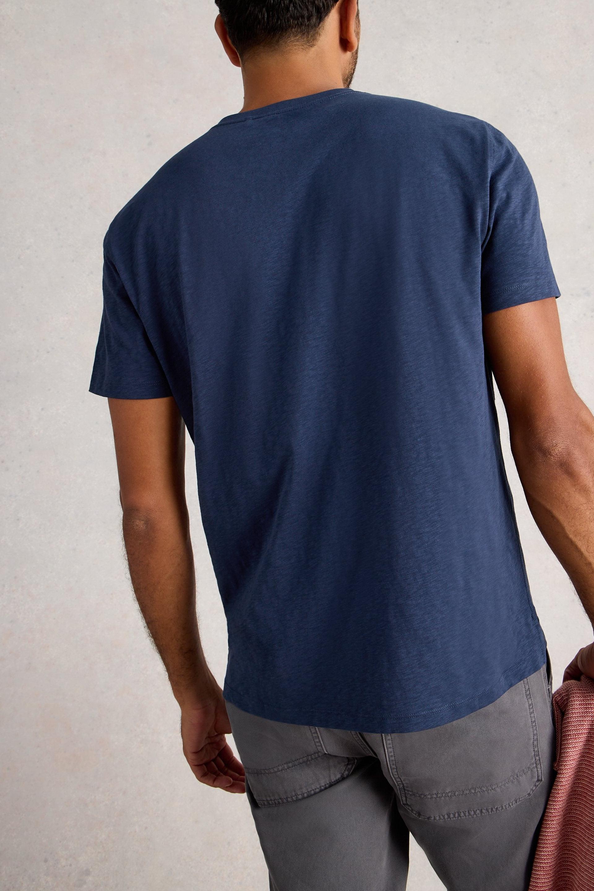 Man wearing a blue cotton t-shirt and gray pants against a plain background