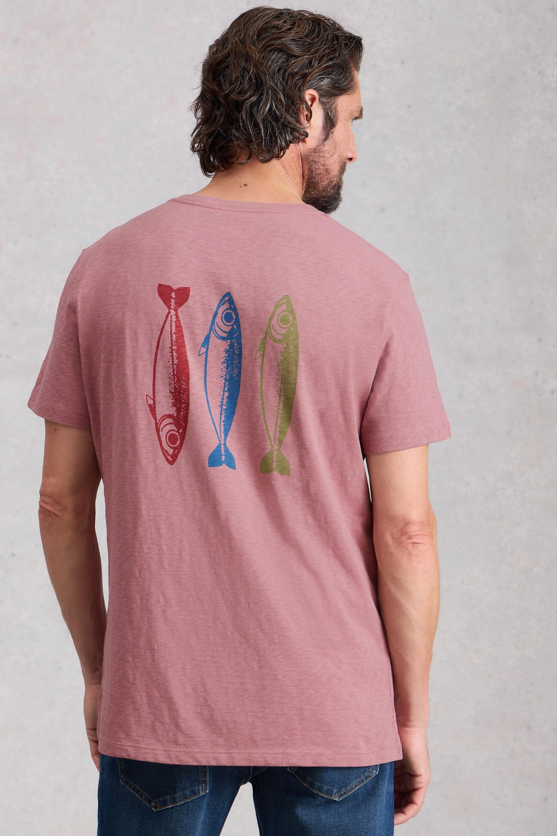 Man wearing a pink t-shirt with colorful fish design on the back against a light gray background