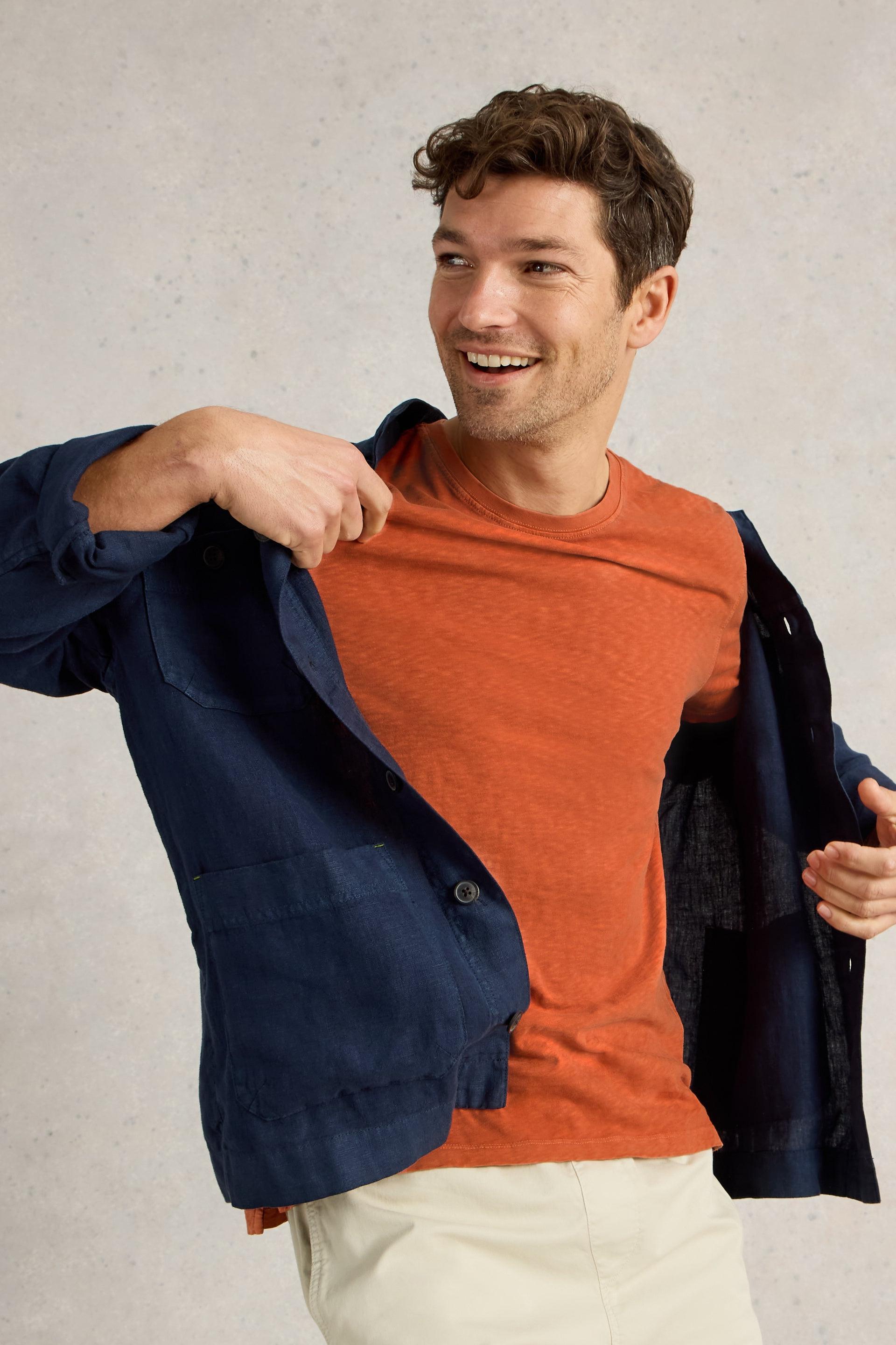 Model looking to the side taking of navy shirt.