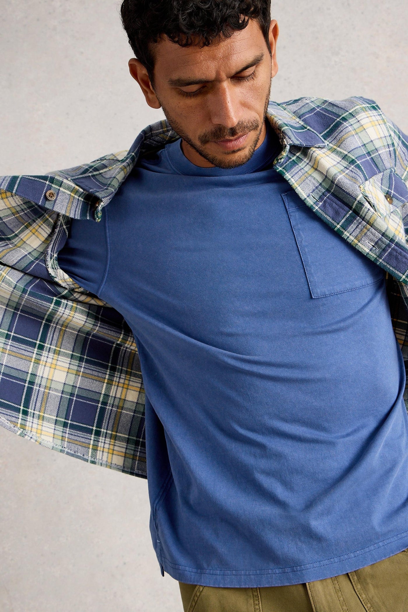 Close up of long sleeve blue organic cotton t-shirt layered under checkered shirt