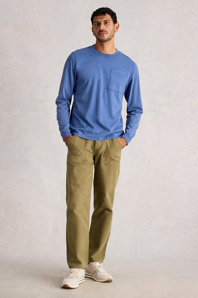 Man standing wearing long sleeve blue organic cotton t-shirt styled with khaki green trousers and white trainers