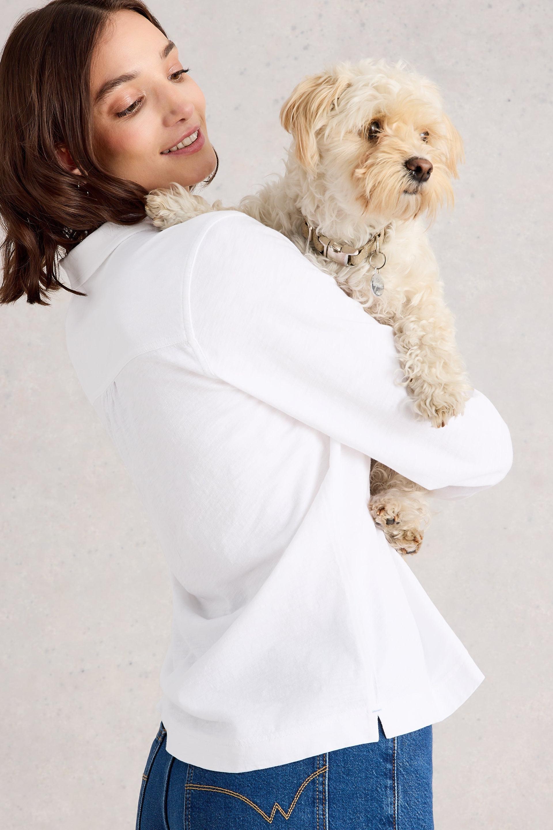 Woman holding a small dog against a plain background