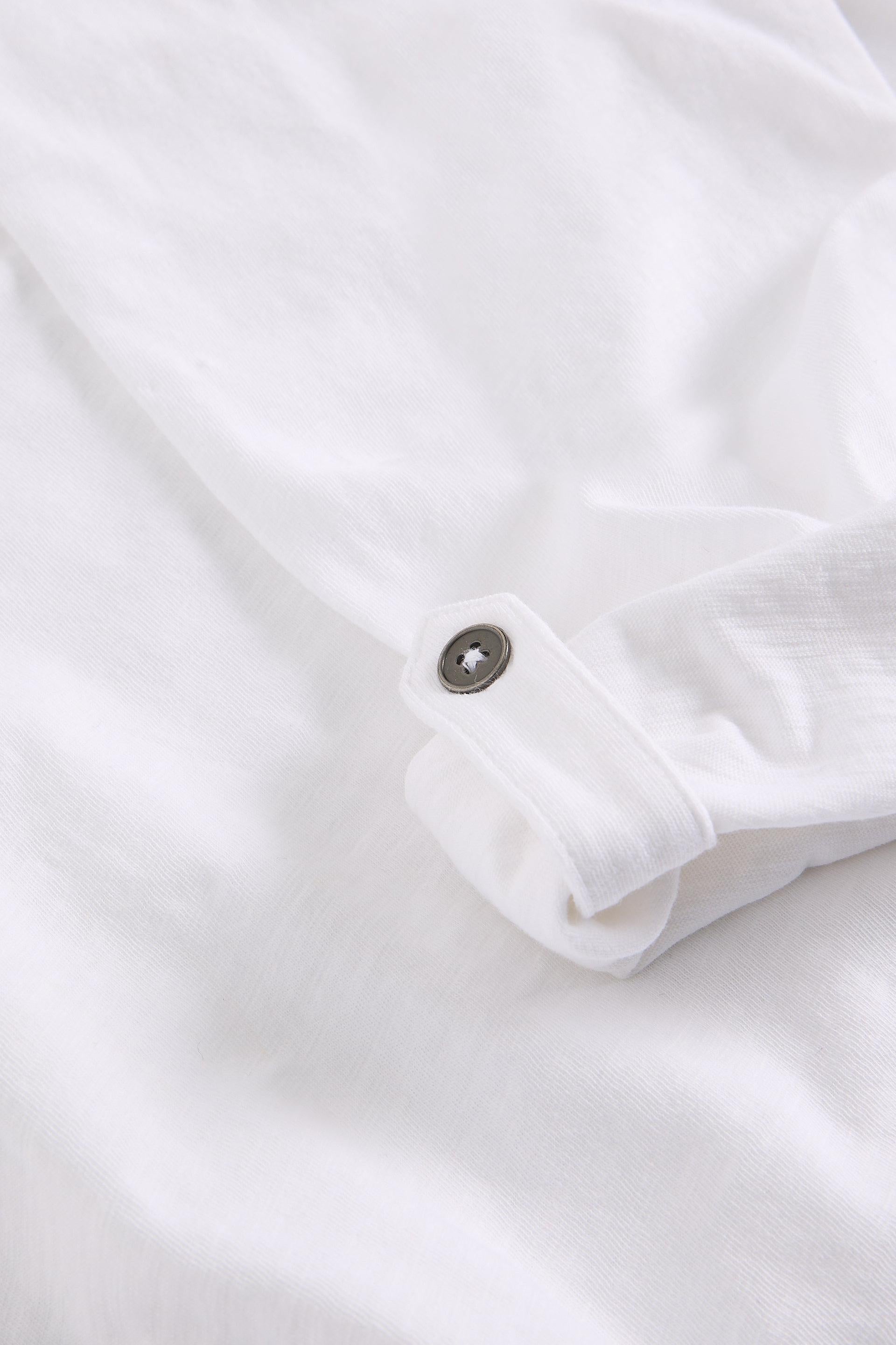 Close-up of a white shirt with a button on a light gray background