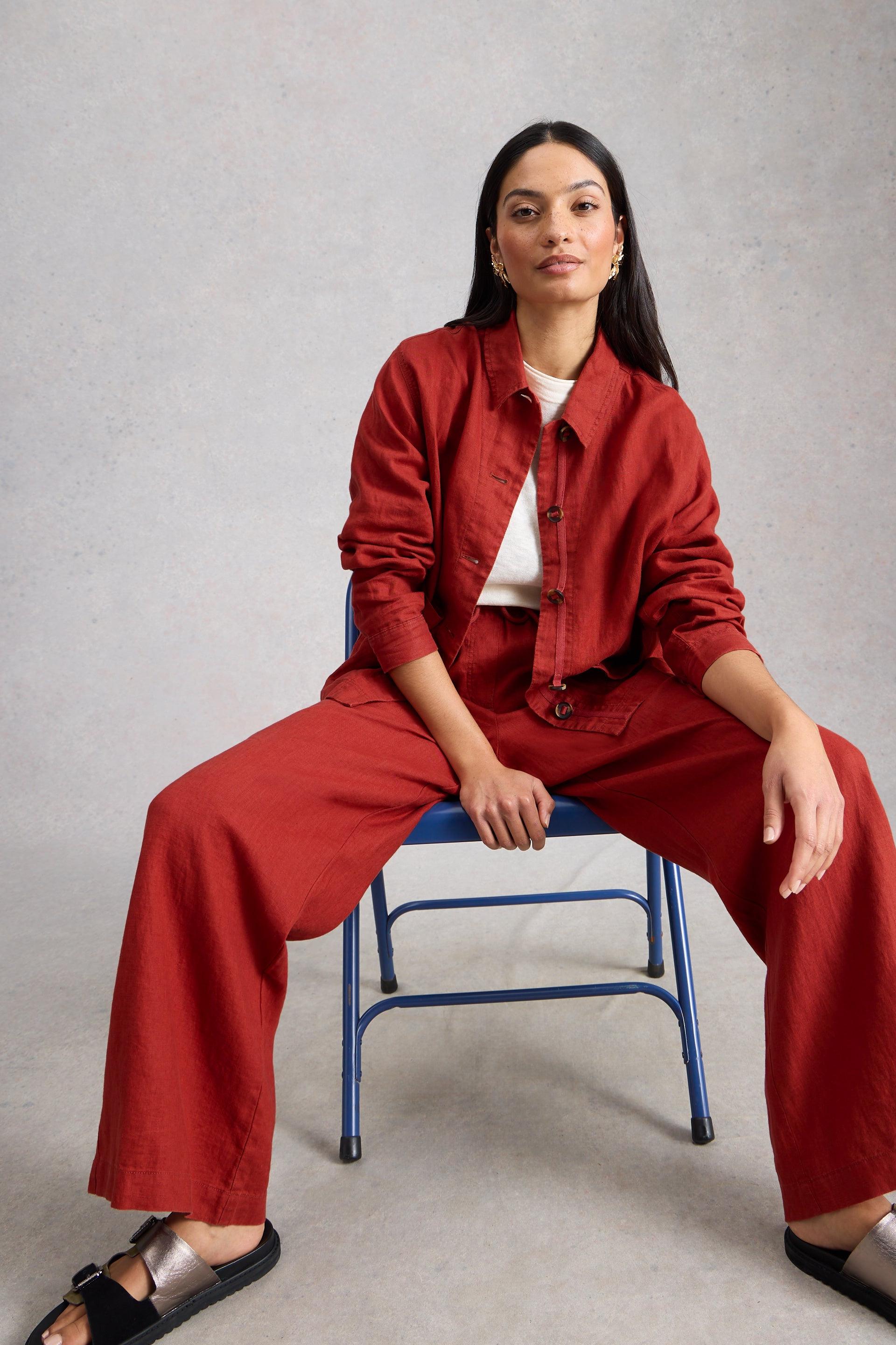 Person wearing a red outfit sitting on a blue chair against a gray background