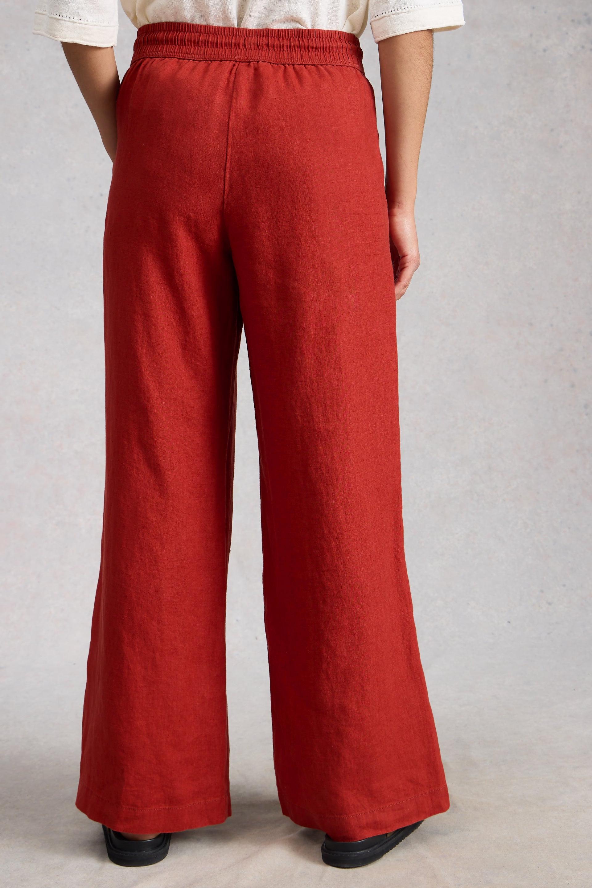 Red wide-leg linen pants worn by a person on a plain background