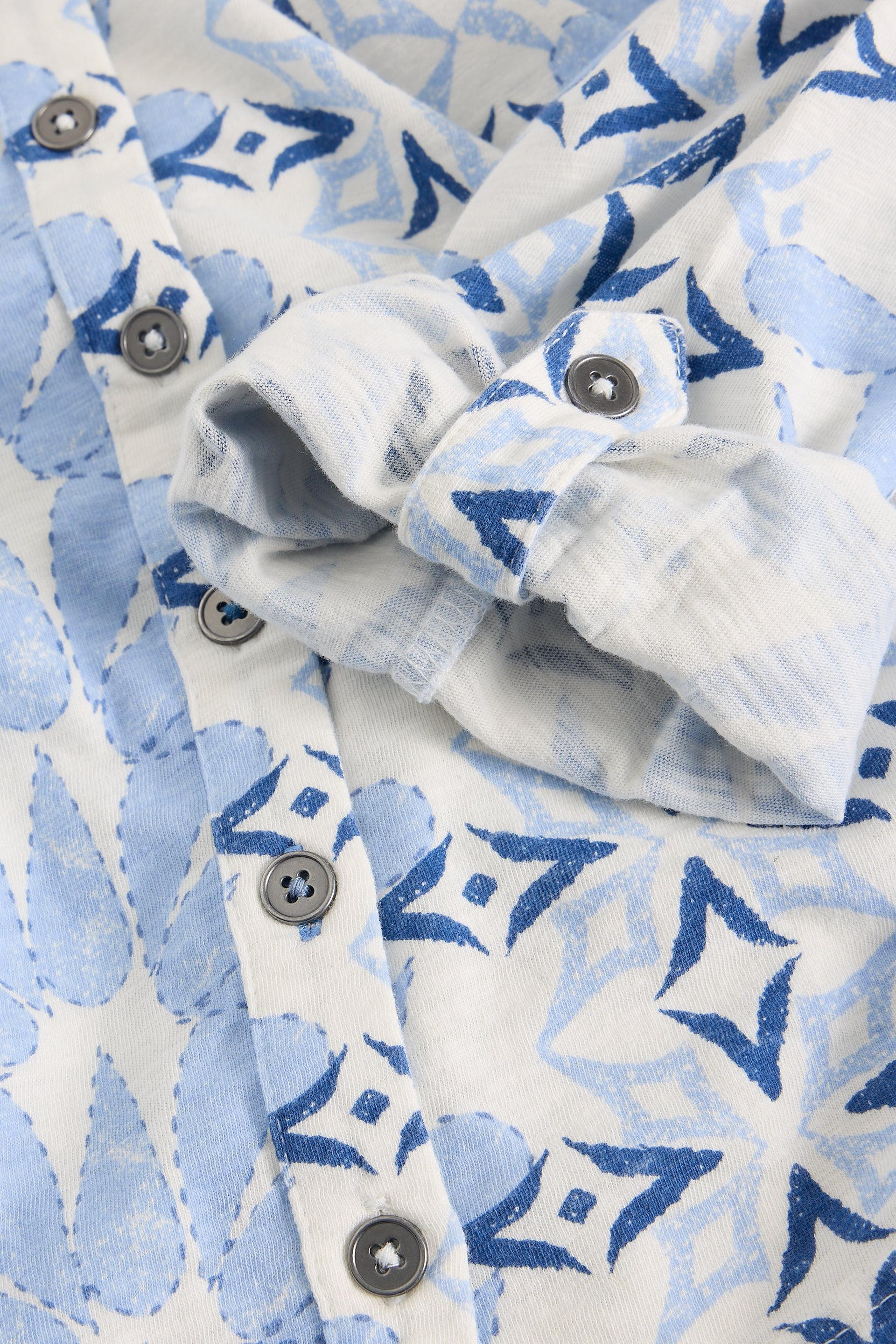 Close-up of a fabric with blue geometric pattern and buttons on a white background