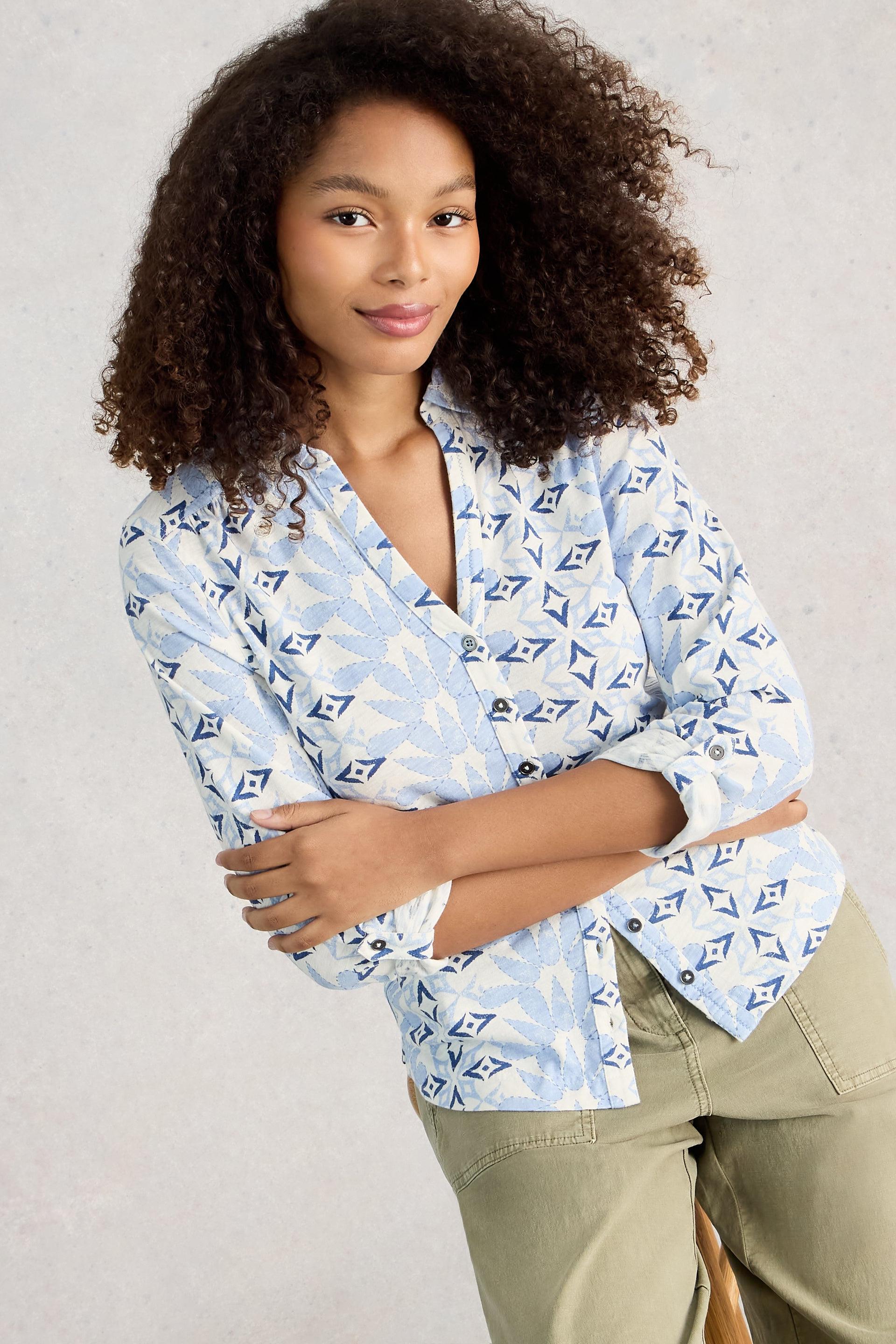 Woman wearing a patterned cotton shirt with rolled-up sleeves against a plain background
