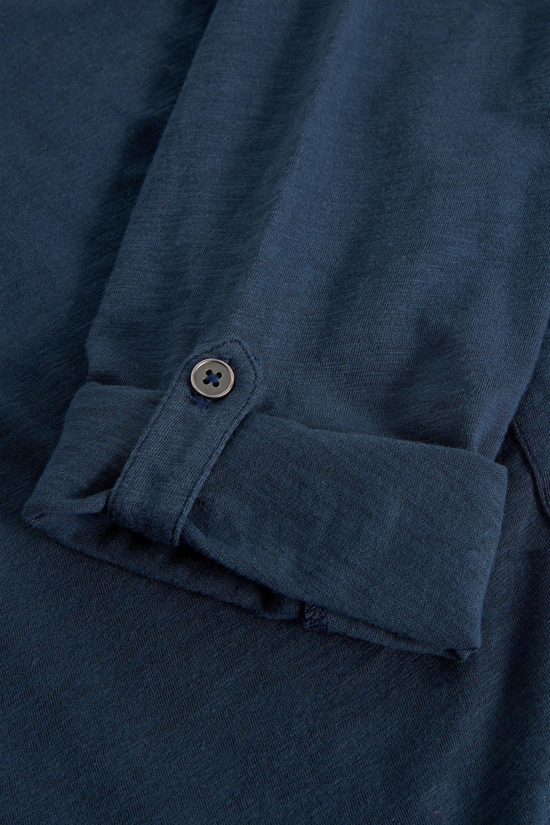 Close-up of a blue shirt with a button on rolled up sleeve
