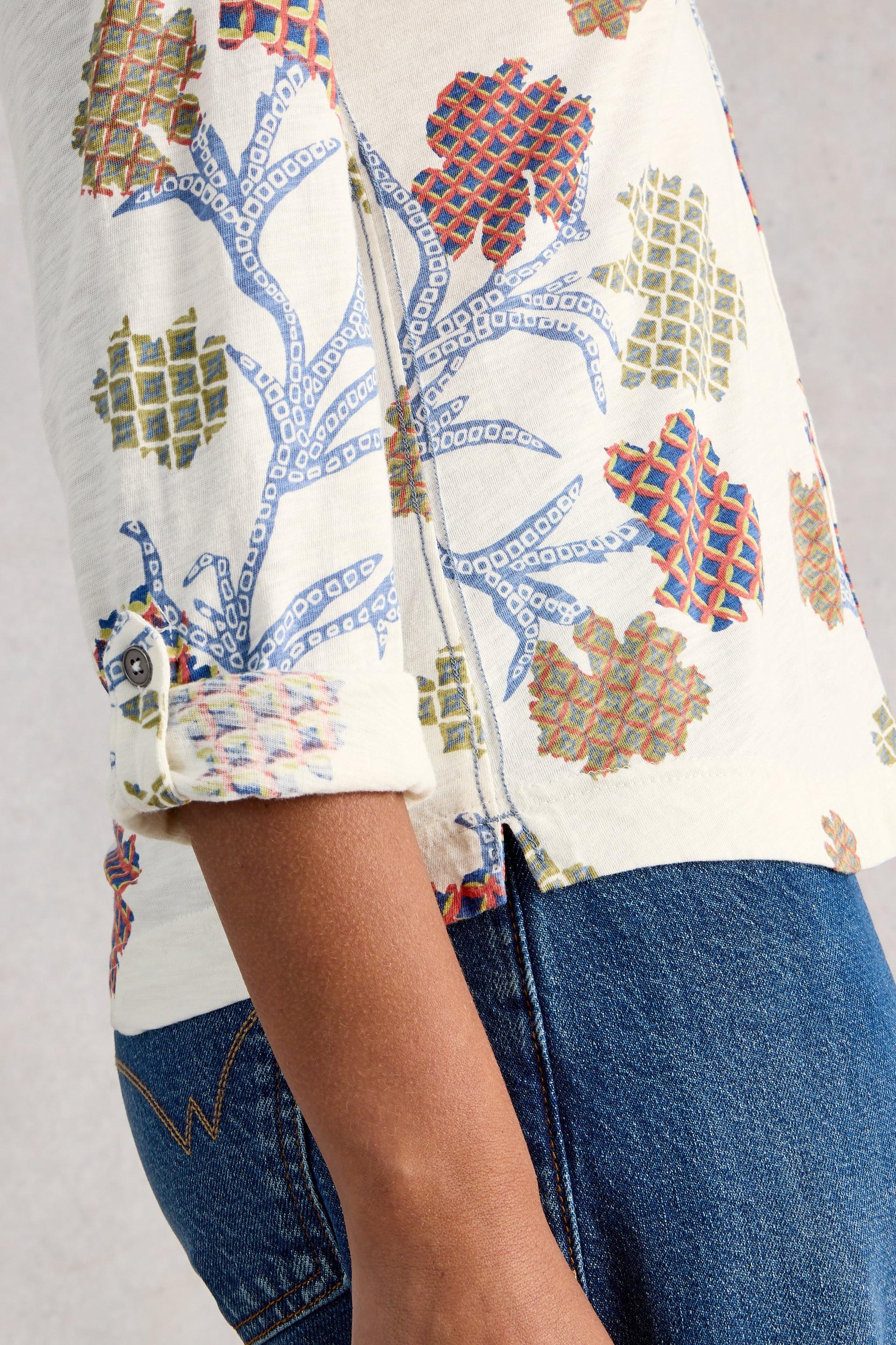 Close-up of a person wearing a patterned shirt and jeans on a plain background