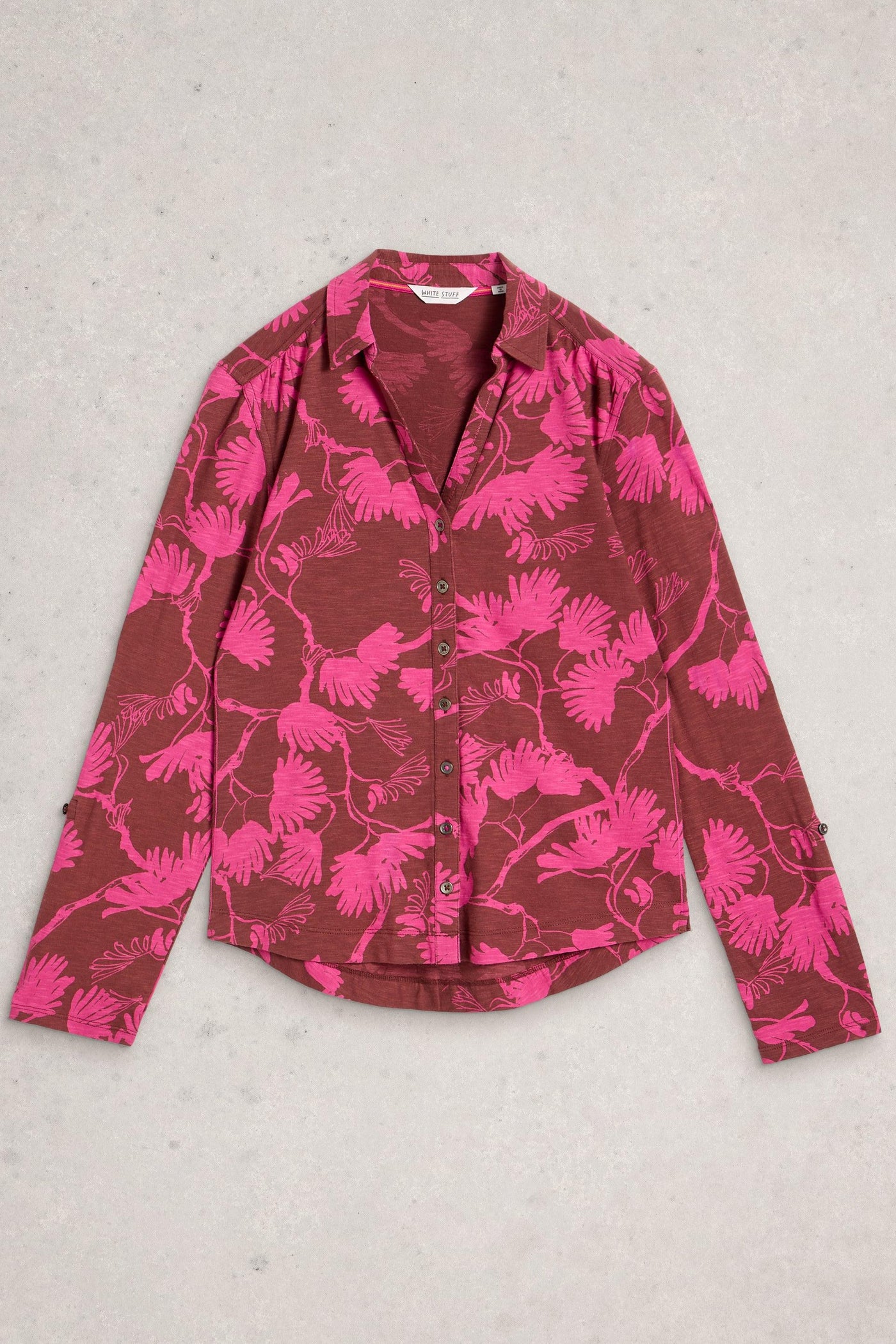 Button up cotton shirt in pink floral print, laid flat on neutral background