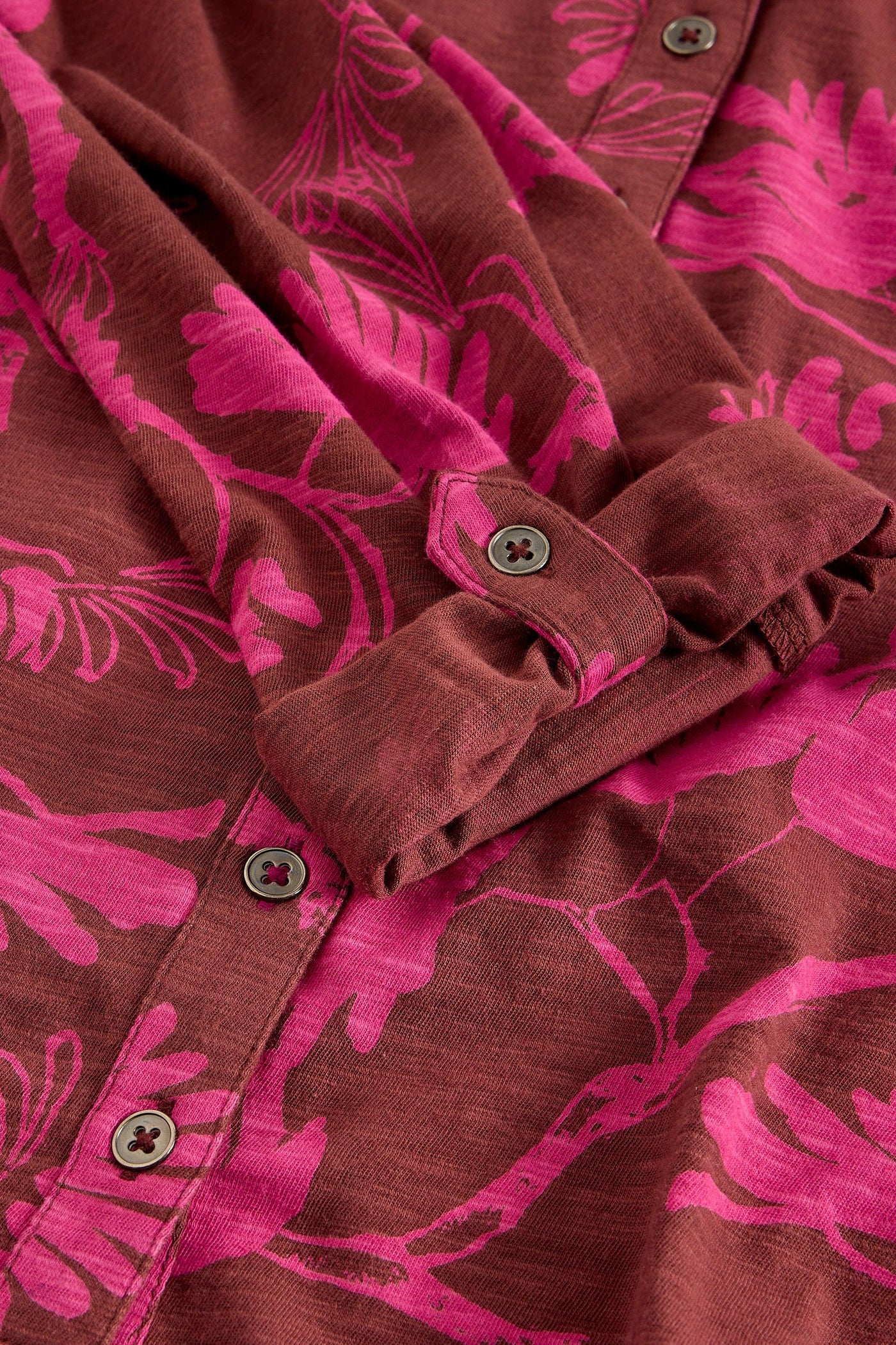 Close-up of button detail on pink floral cotton shirt