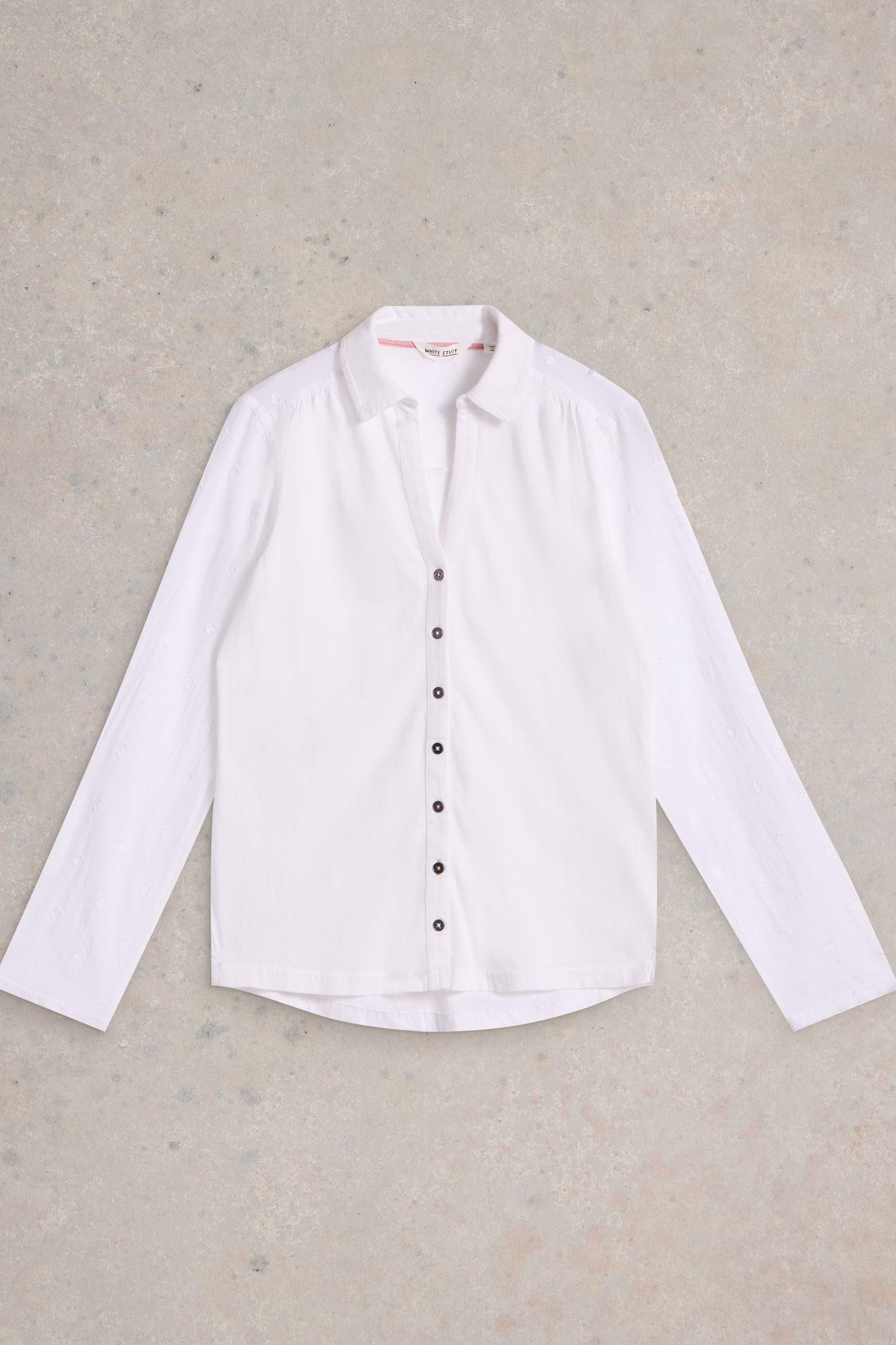 White cotton shirt with black buttons on a beige background