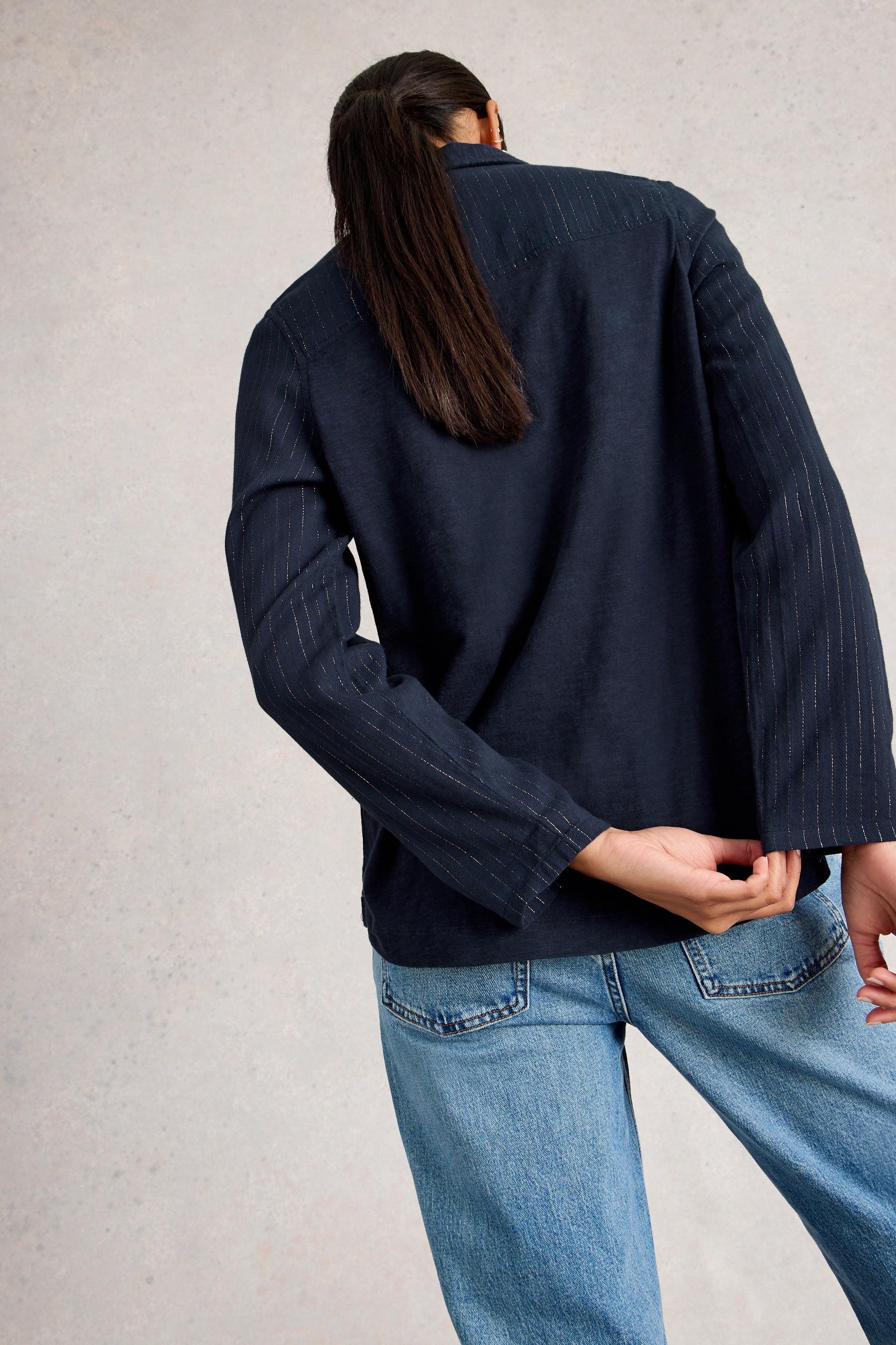 Person wearing a navy organic cotton blouse and blue jeans against a light gray background