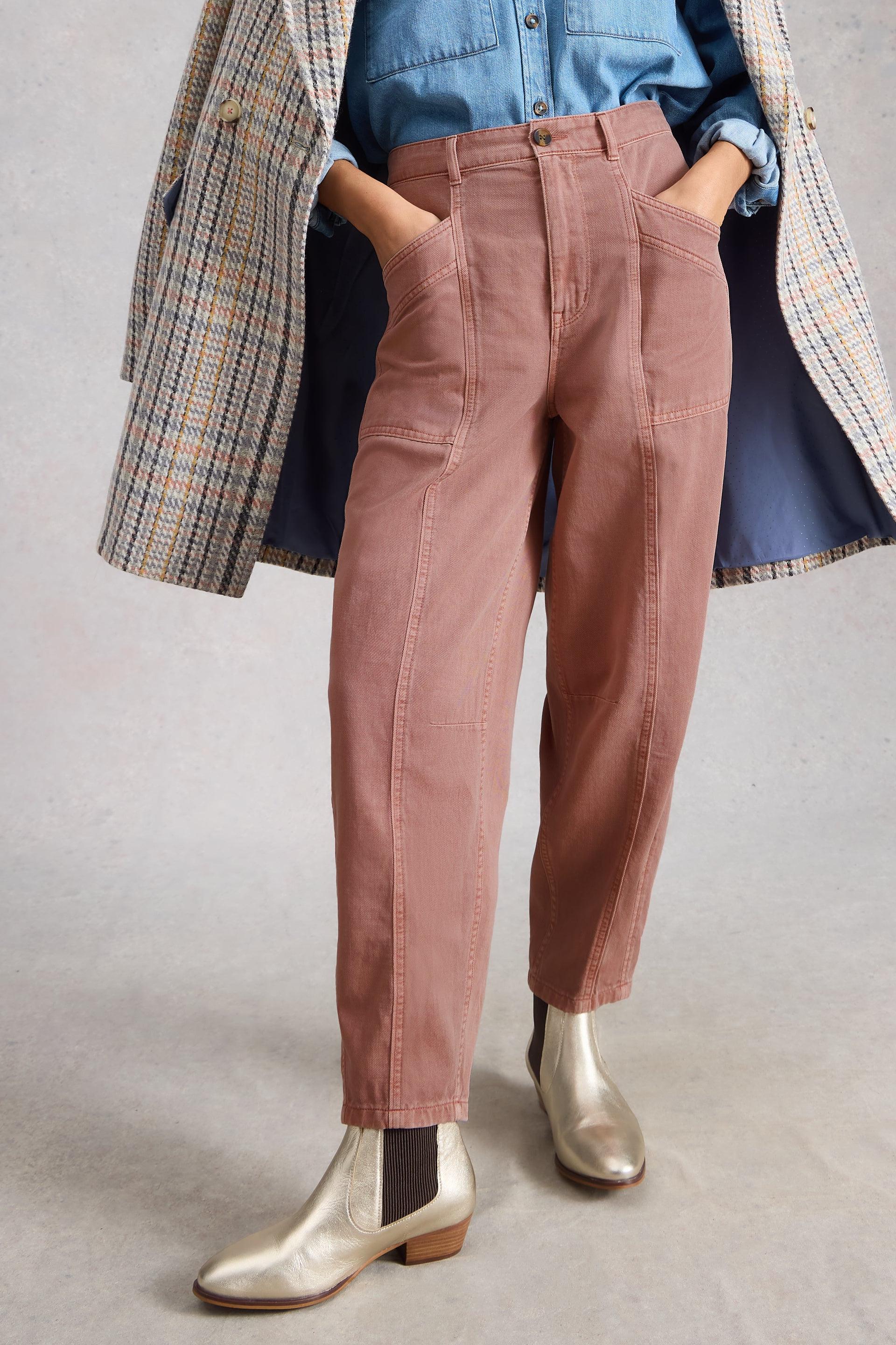 Person wearing pink organic cotton pants, blue shirt, plaid coat, and silver boots on a plain background