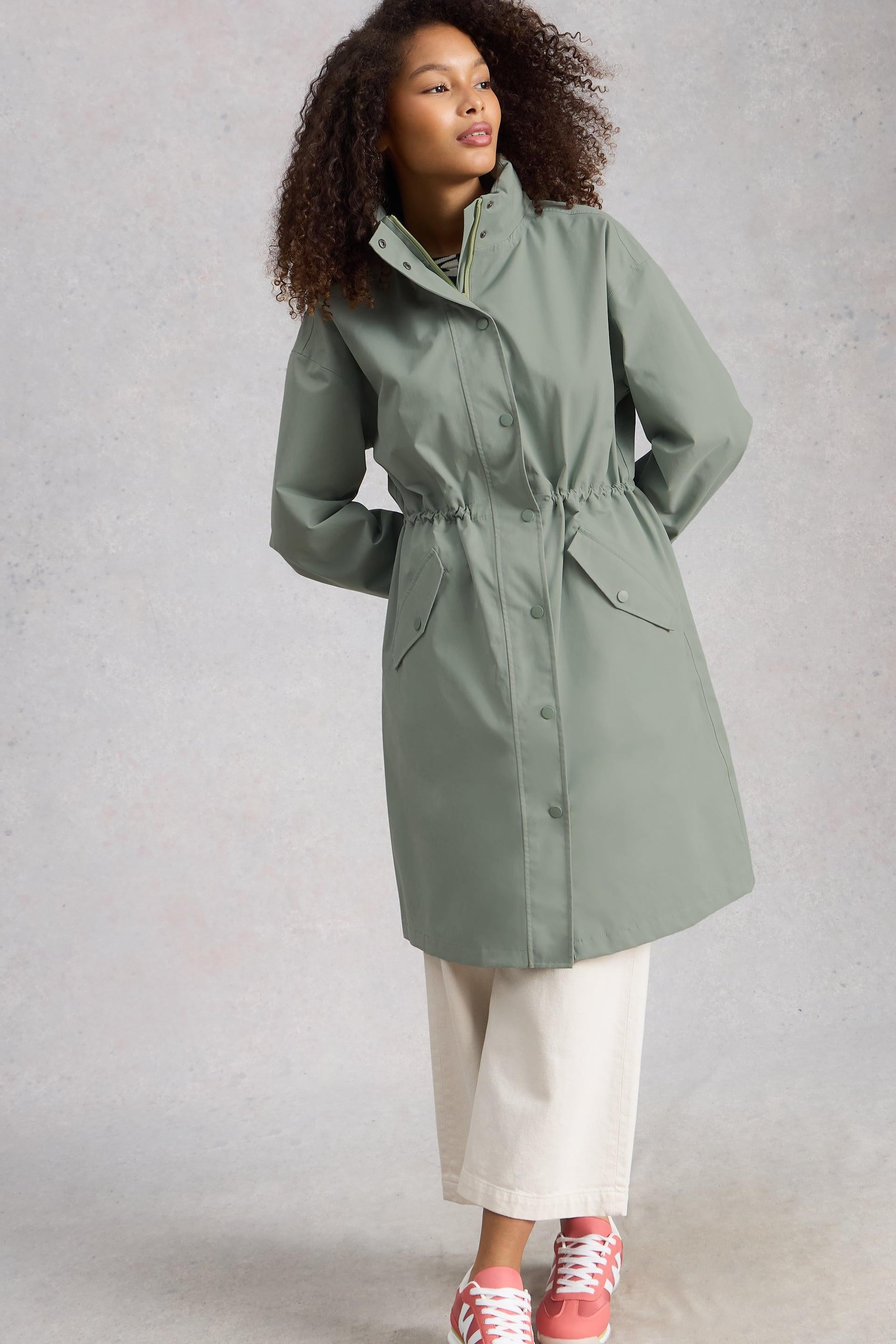 Person wearing a green waterproof raincoat on a plain background