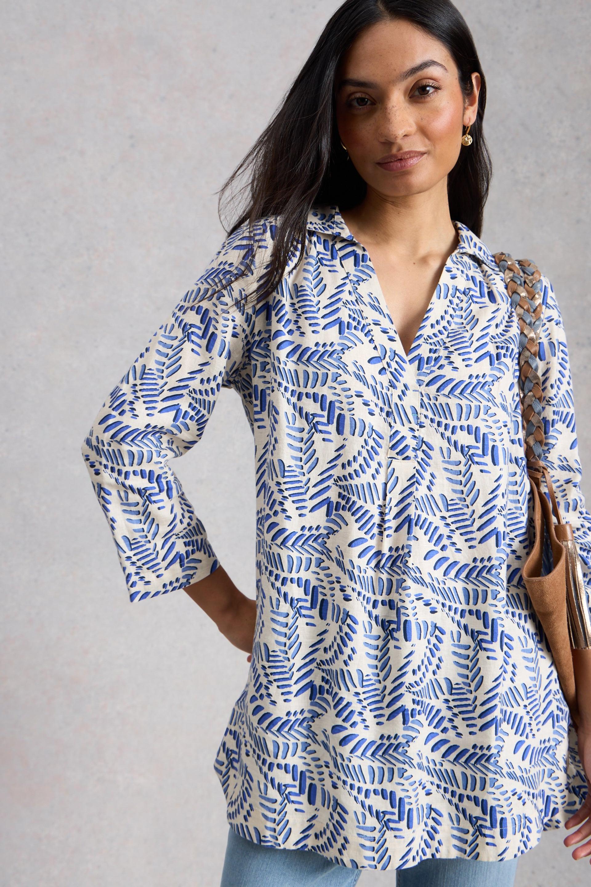 Woman wearing a blue and white patterned tunic against a gray background
