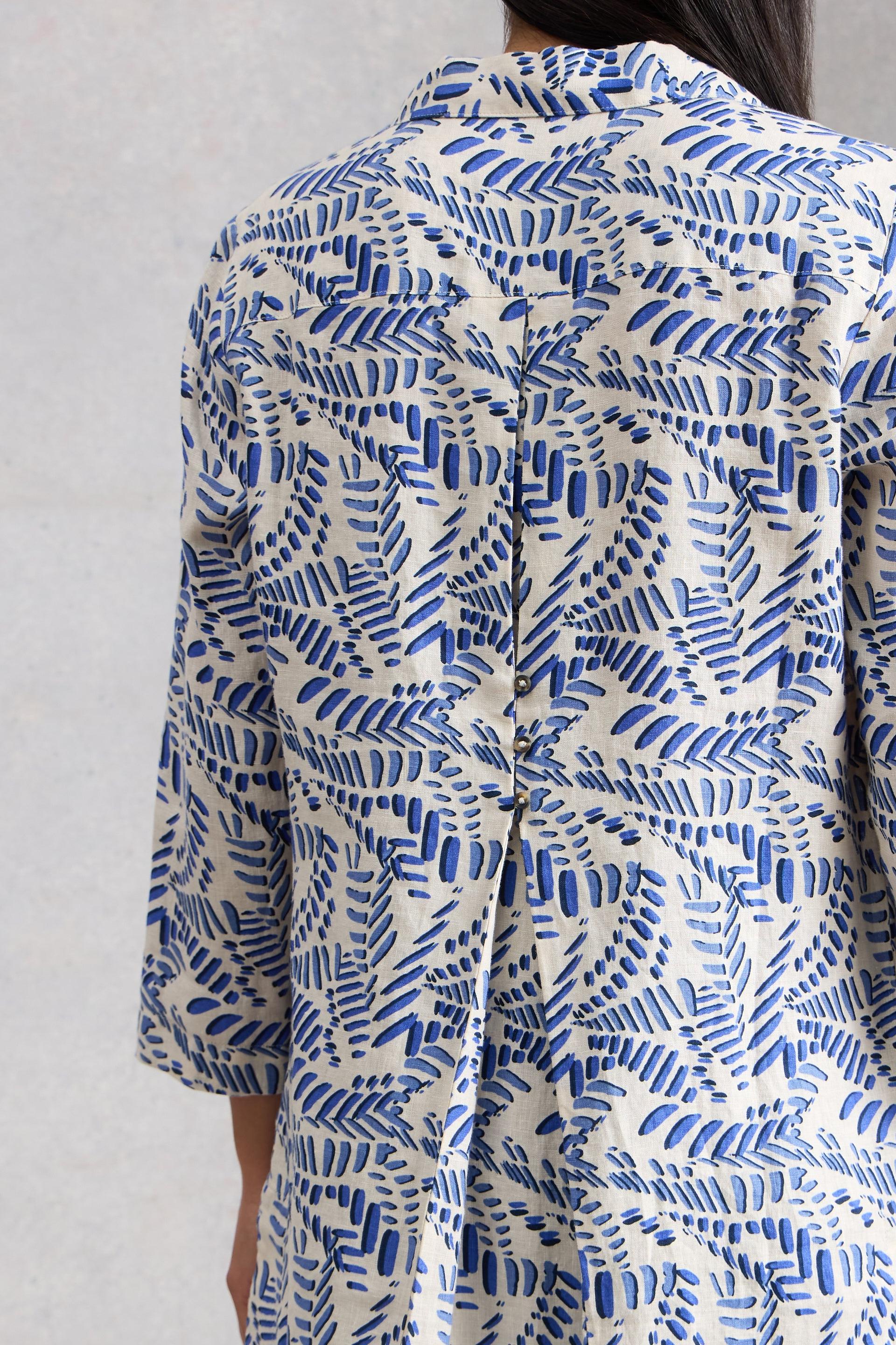 Blue and white patterned tunic worn by a person against a plain background
