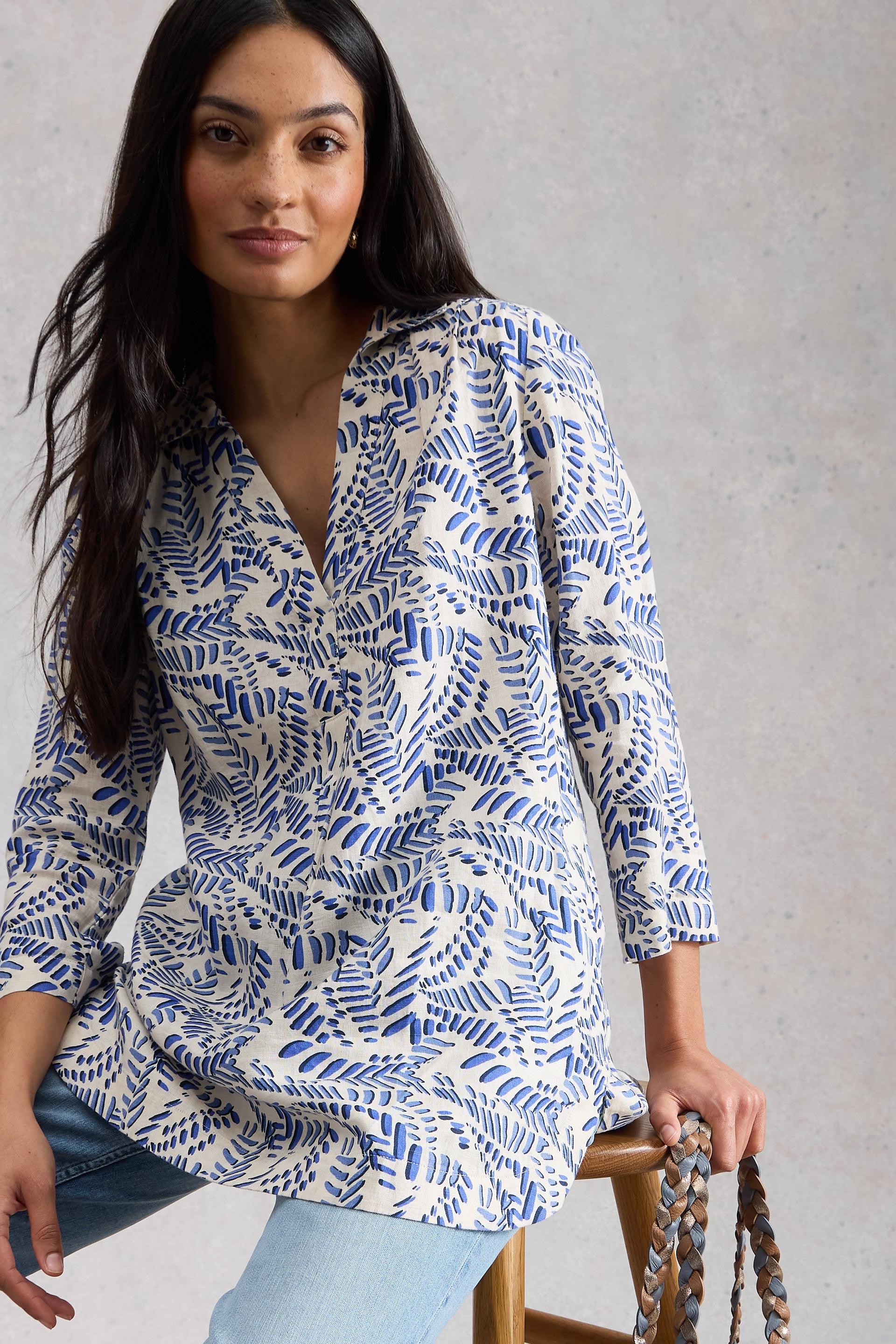 Woman wearing a blue and white patterned tunic against a gray background