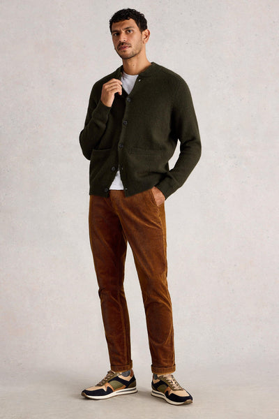 Man wearing green wool cardigan styled with rust coloured trousers and multicolour trainers