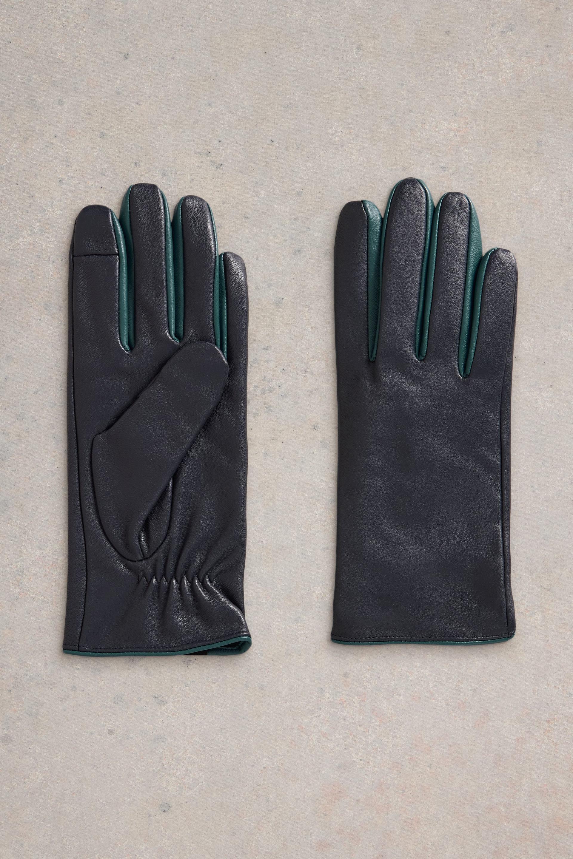 Flat lay of navy leather gloves with turqoise details on neutral background