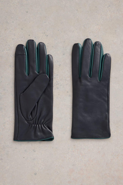 Flat lay of navy leather gloves with turqoise details on neutral background