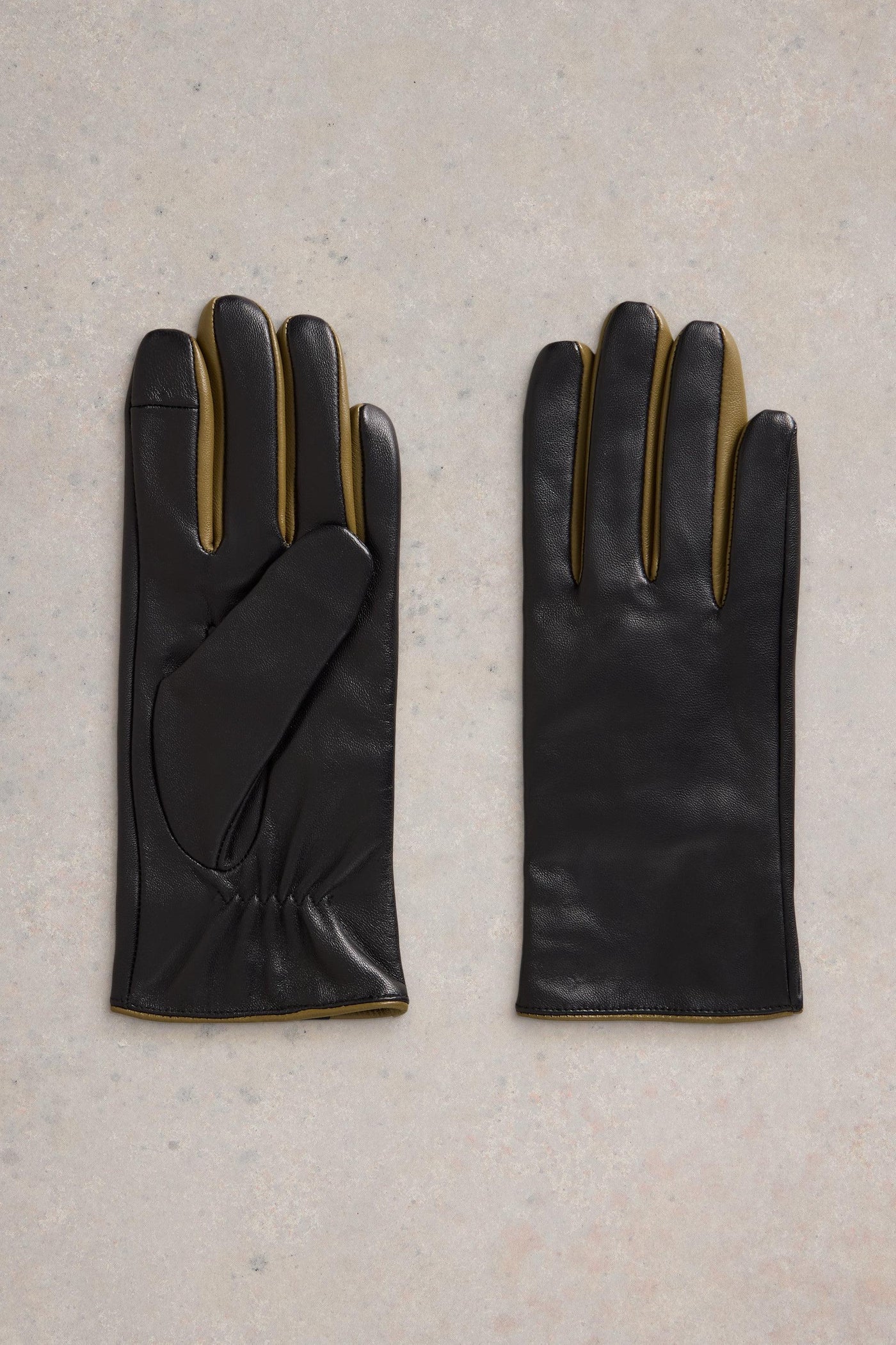 Flat lay of black leather gloves with mustard detail 