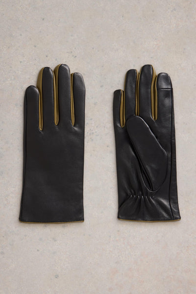 Flat lay of black leather gloves with mustard detail on a neutral background