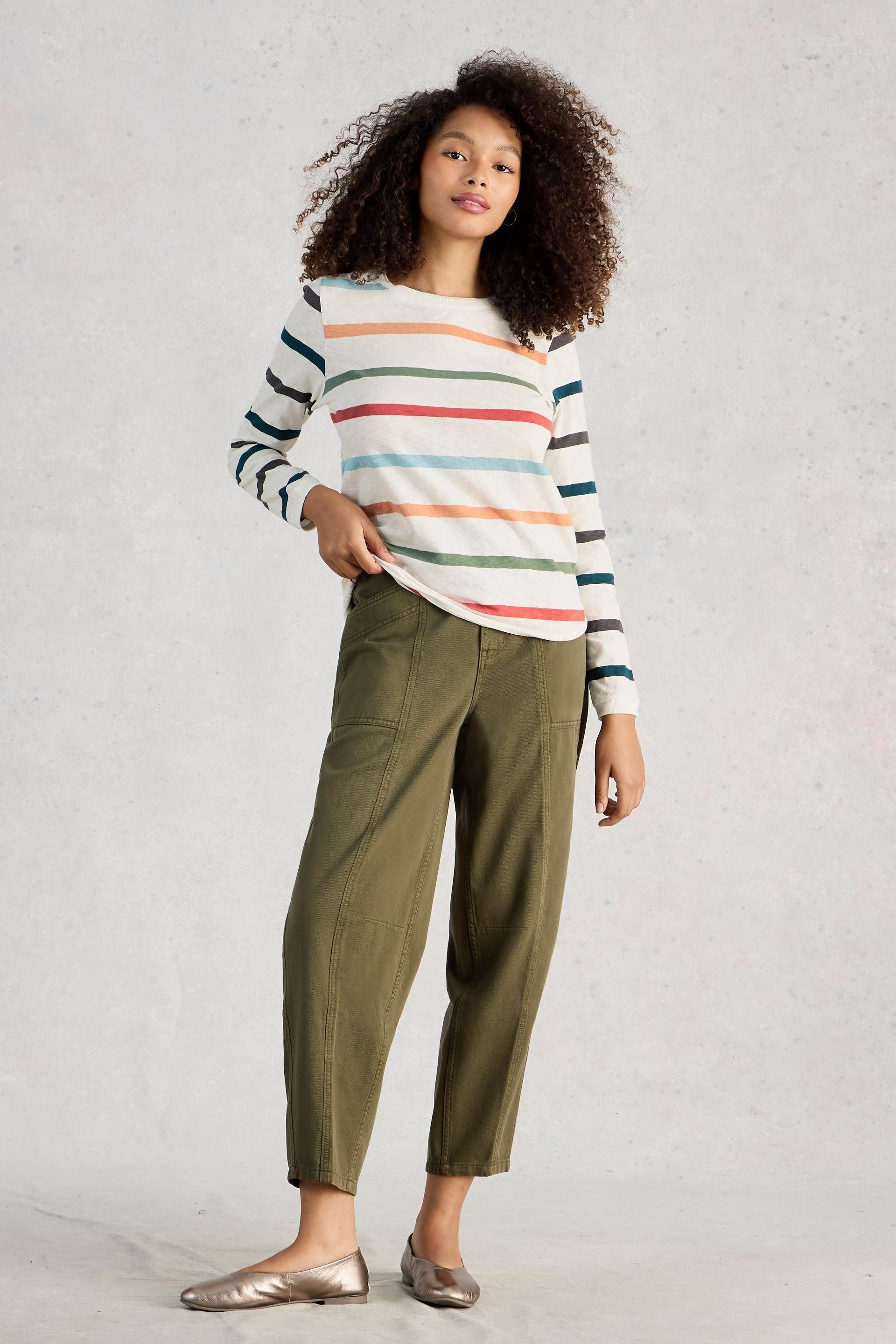 Woman wearing a striped cotton top and green pants against a plain background